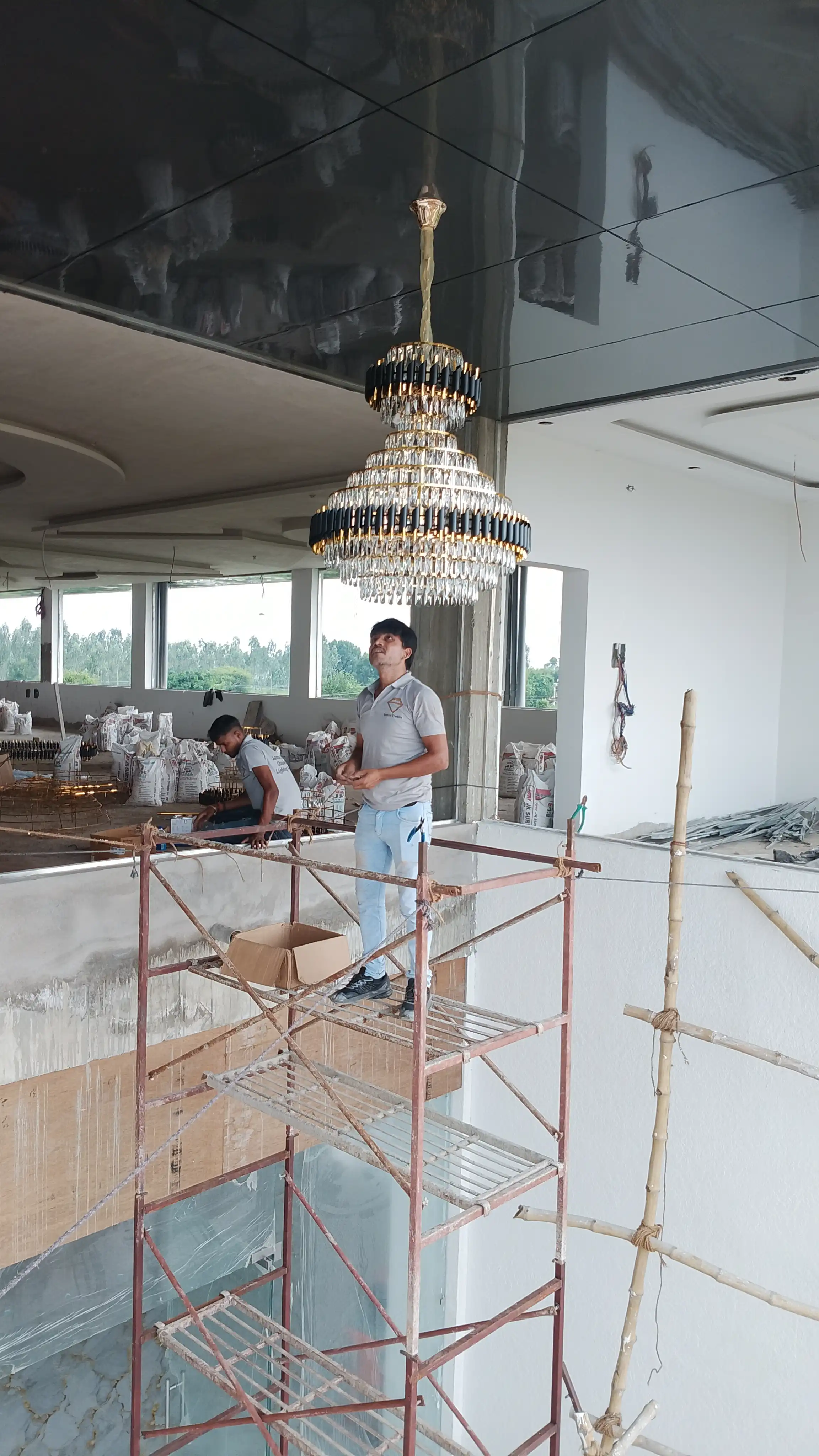 Black Mamba tiered crystal chandelier being installed on scaffolding by professional chandelier installers