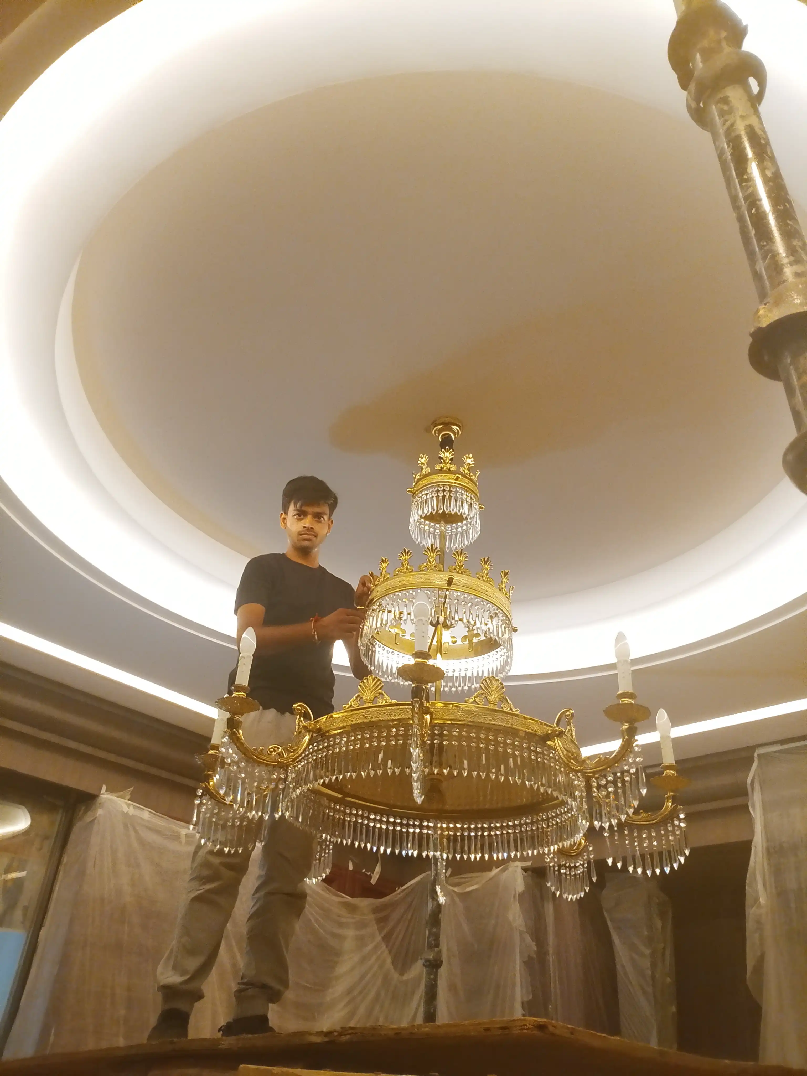 Brass crystal chandelier being installed by professional chandelier installation team