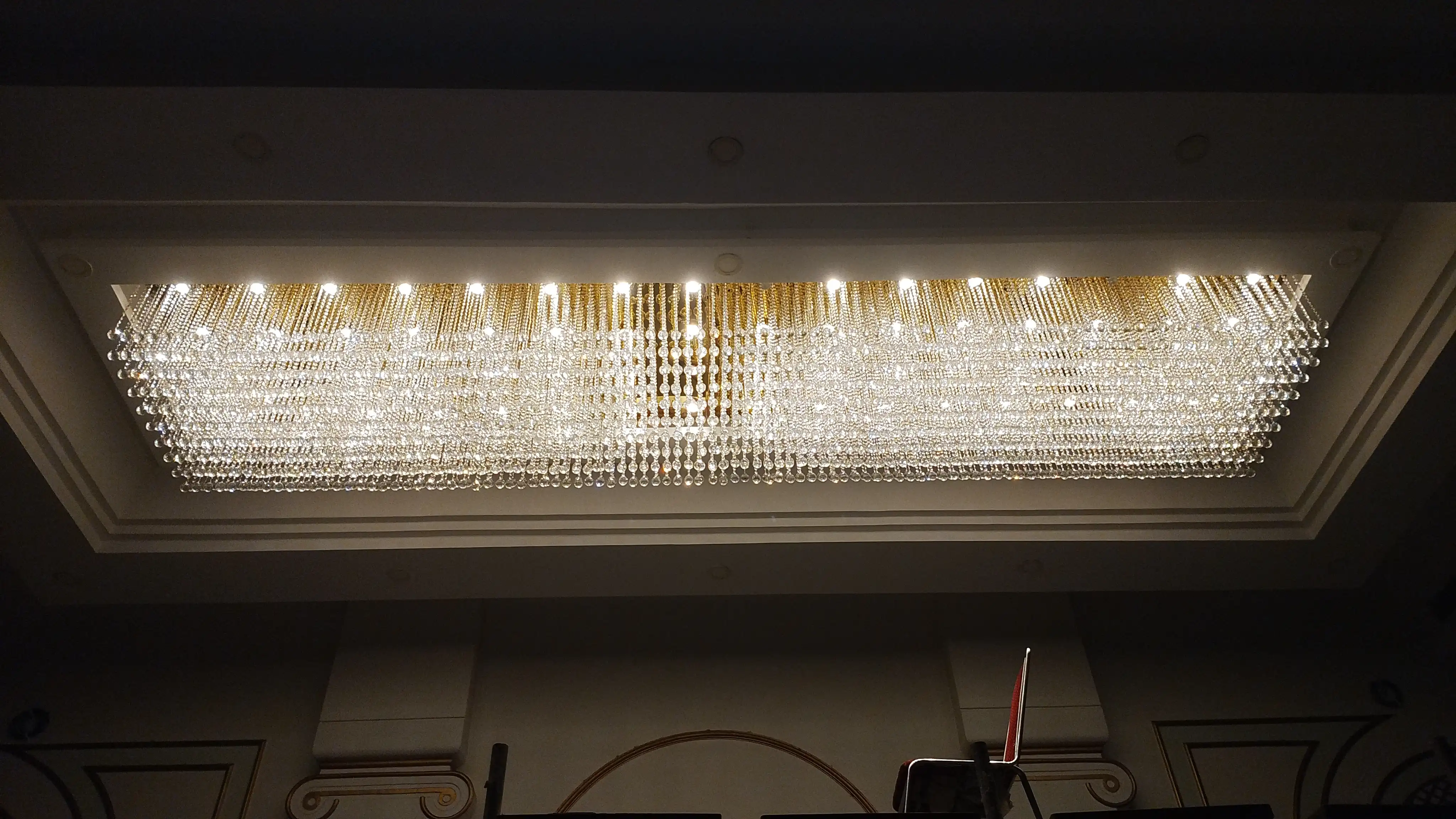 Large rectangular crystal chandelier with illuminated crystal strands in a luxury interior