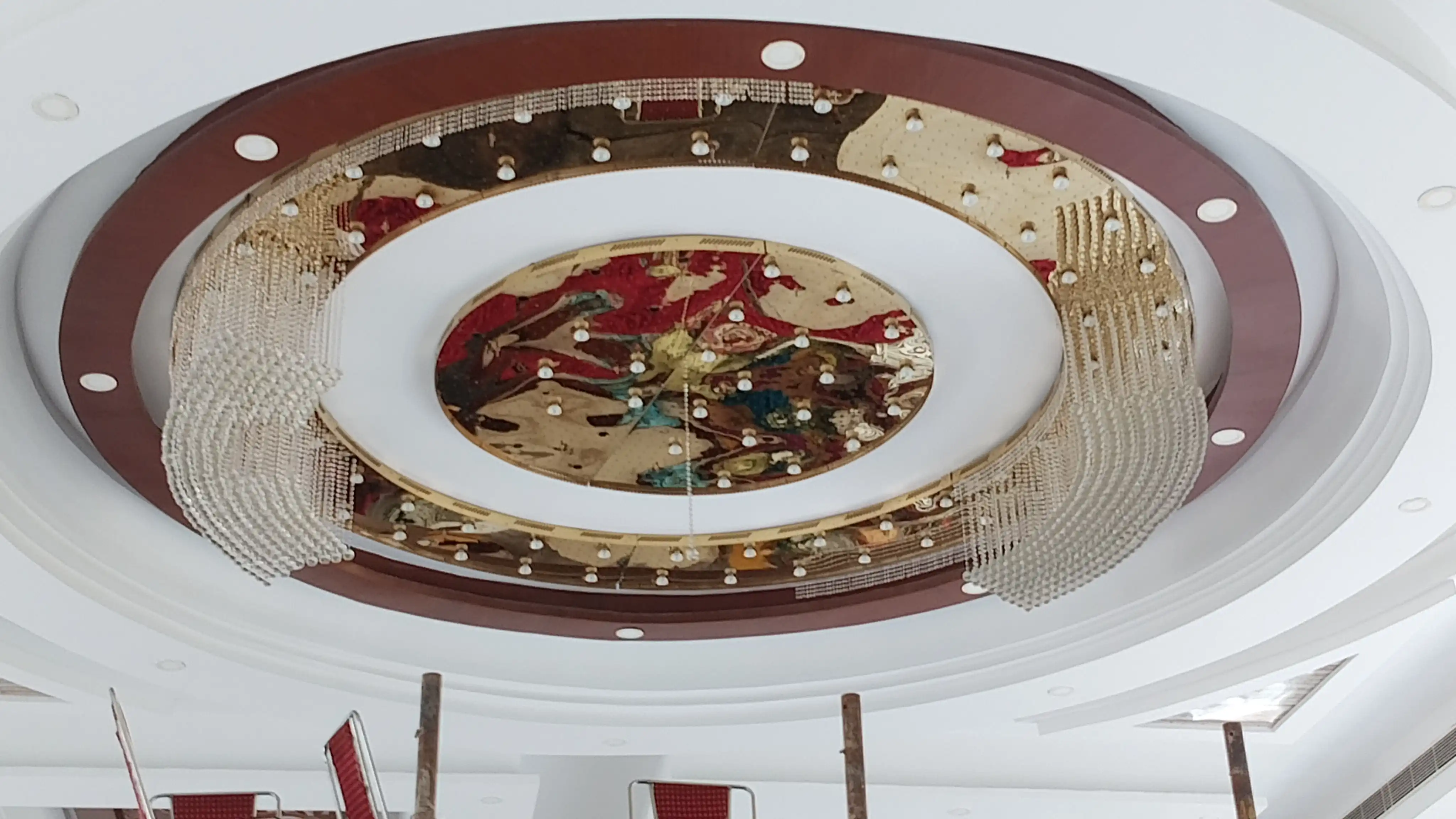 Technicians installing a large custom circular crystal chandelier in a luxury interior