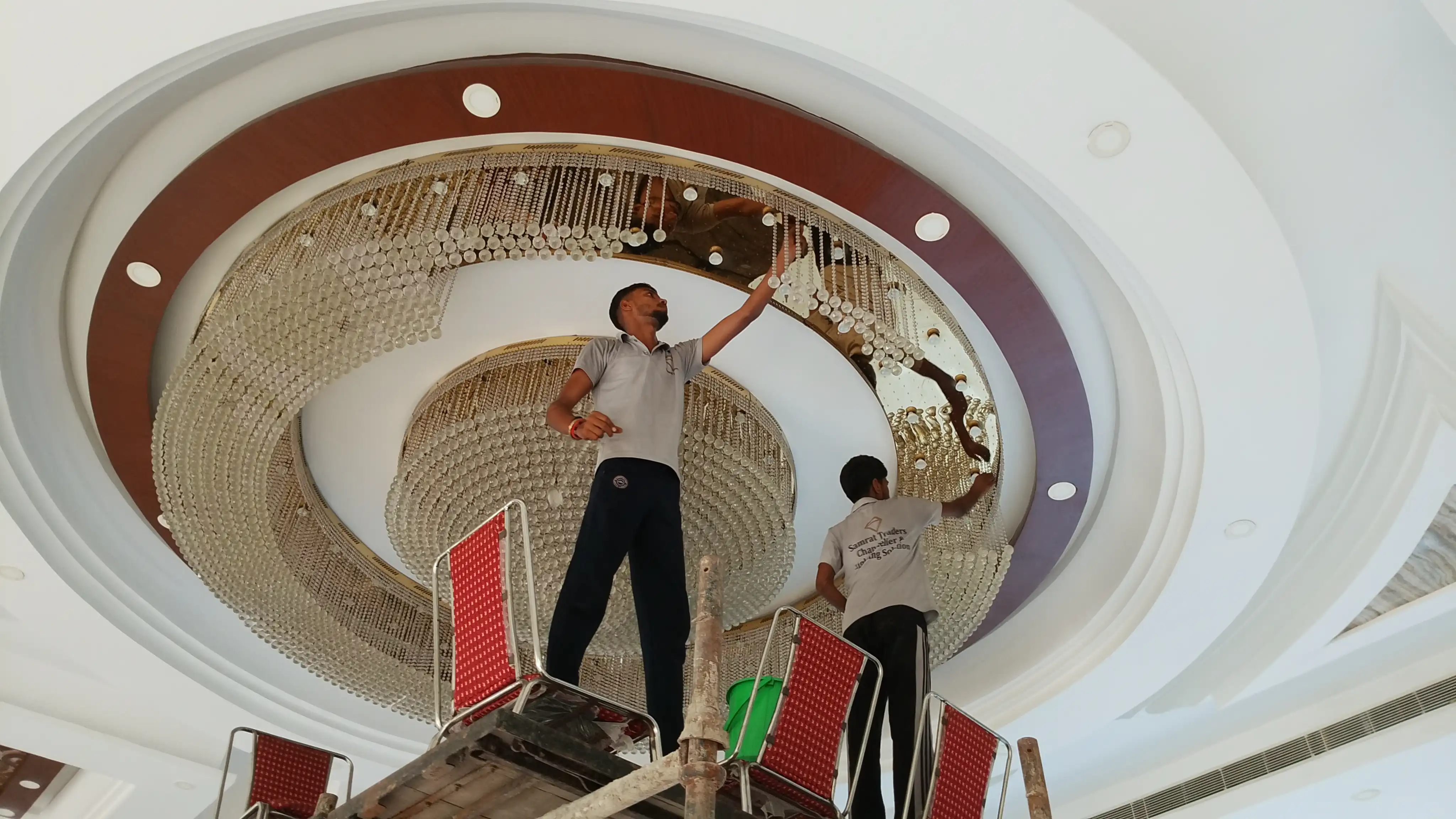 Chandelier installation team working on a large circular crystal chandelier using scaffolding