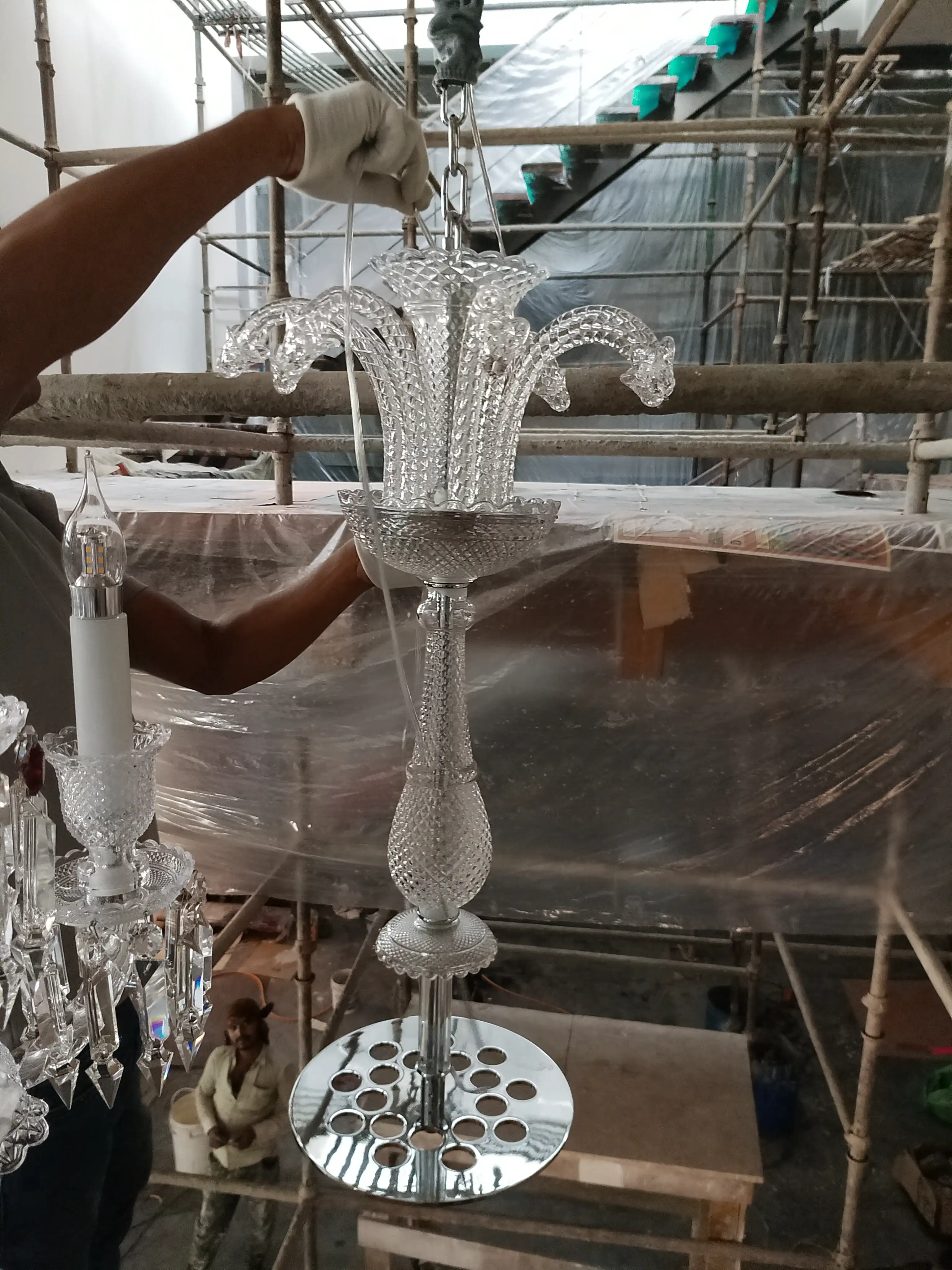 China imported crystal chandelier arm and decorative component being assembled during luxury chandelier installation
